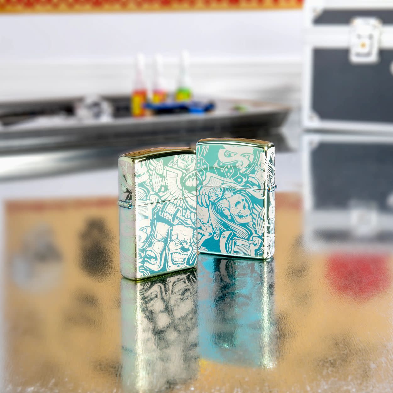 Lifestyle image of two Laser 360?? Tattoo Theme Design High Polish Teal Windproof Lighters standing on a table with tattoo equipment.
